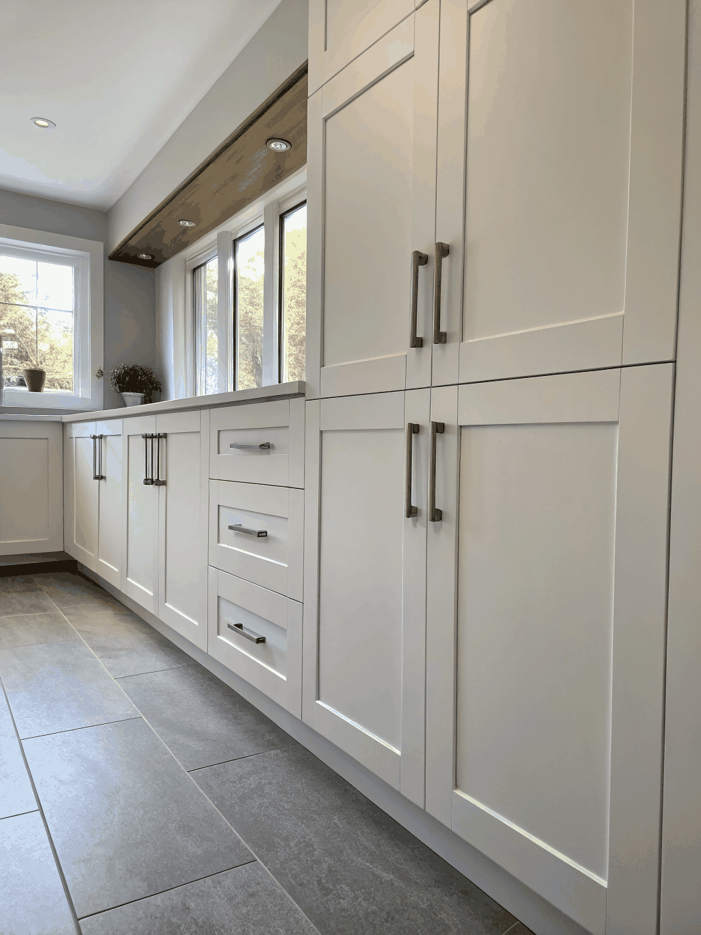 Custom white shaker cabinets with walnut accents in a bright coastal kitchen